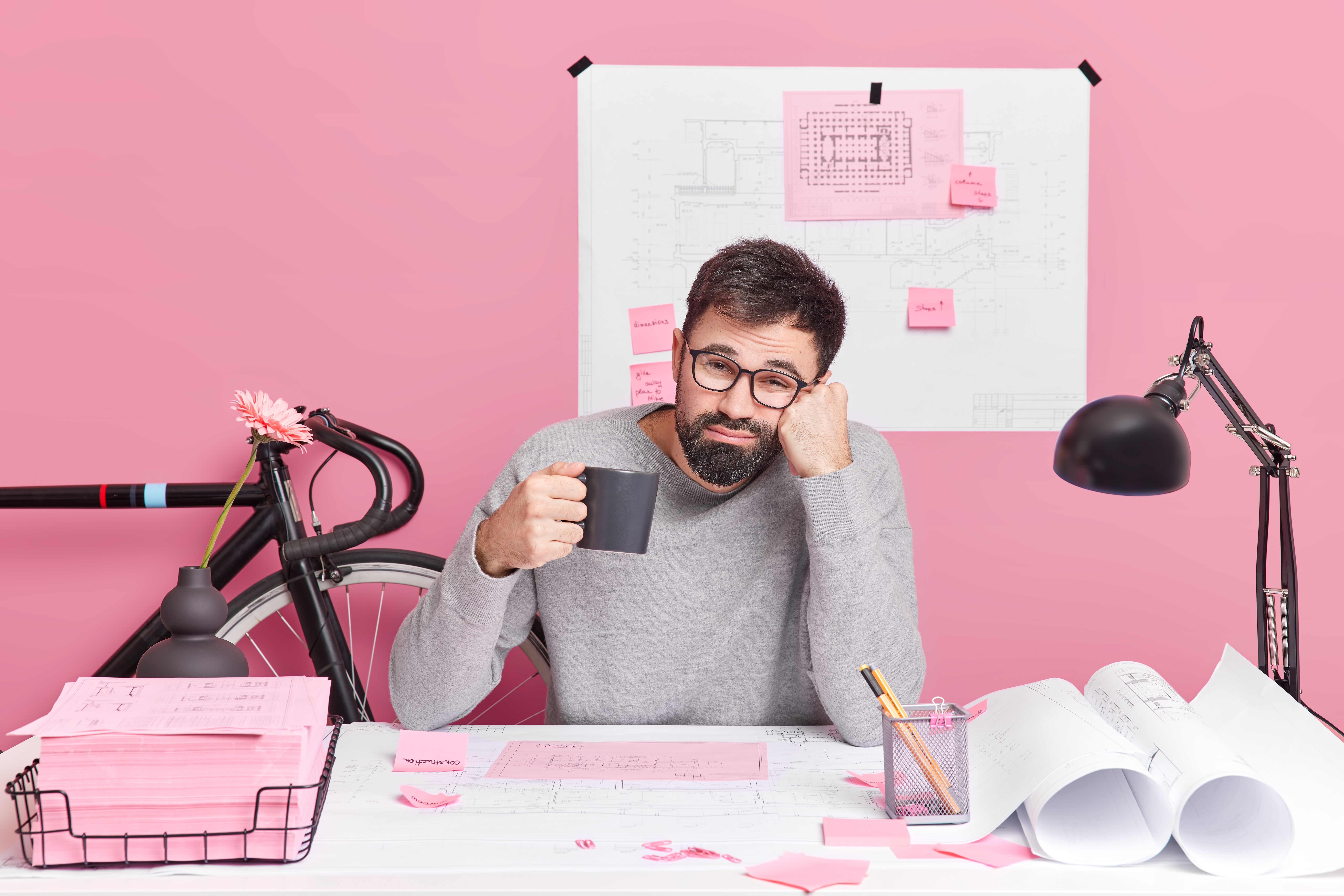 Engineering construction and architecture concept. Tired male office worker drinks refreshing coffee works all night at urgent task has deadline to finish work pose at desktop in coworking space. - Bidaya Global - Credits : Freepik