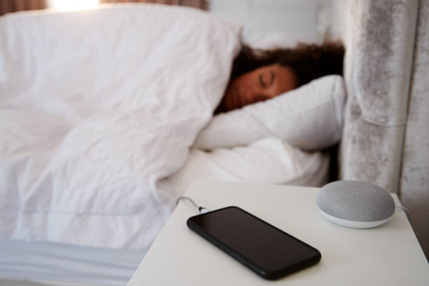 Woman Asleep In Bed With Mobile Phone And Voice Assistant On Bedside Table - Bidaya Global